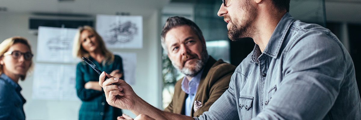 Young designer giving some new ideas about project to his partners in conference room. Business people discussing over new business project in office.