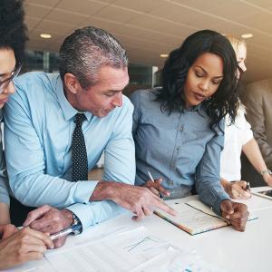 Black and white group of people doing teamwork in contemporary office.