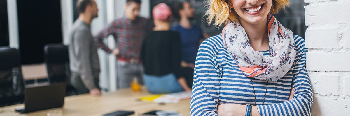 Photo of young business woman in a conference room, with a group of coworkers in backside