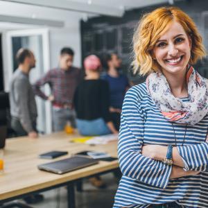 Photo of young business woman in a conference room, with a group of coworkers in backside