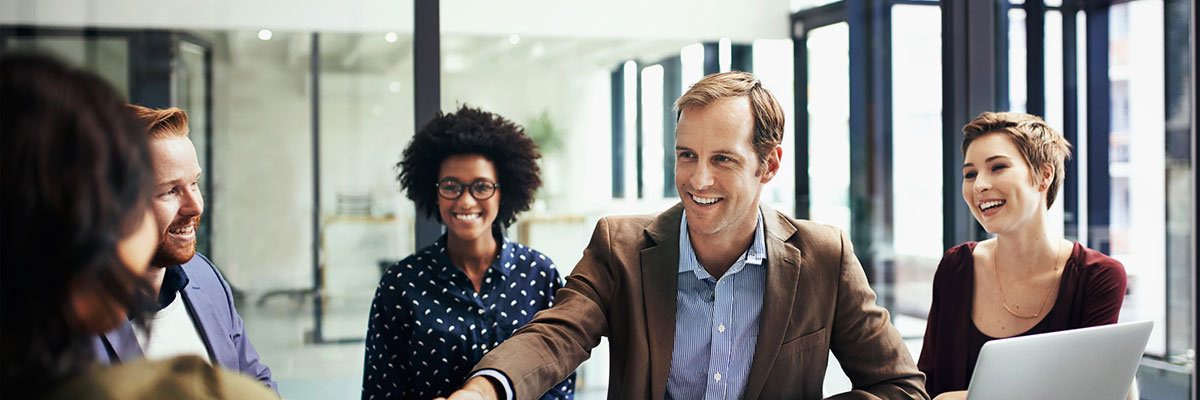 Shot of colleagues shaking hands during a meeting at work