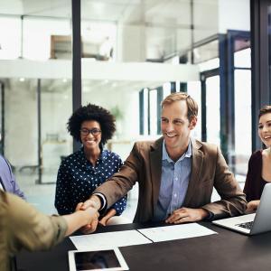 Shot of colleagues shaking hands during a meeting at work