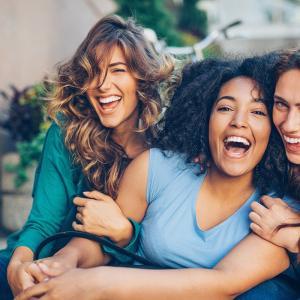 Three young women laughing outdoors