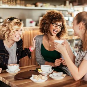 Close up of best friends using a mobile phone while at a cafe